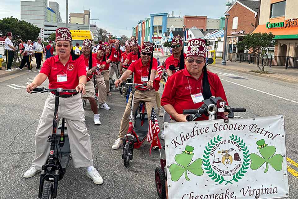 Khedive Shriners riding scooters in a parade