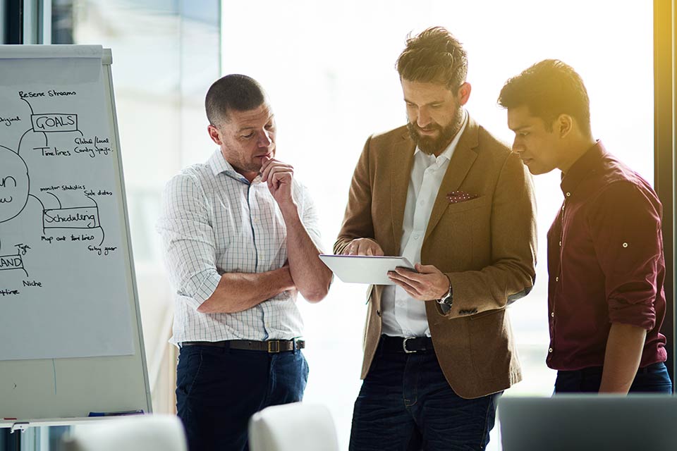 three men reviewing notes during meeting